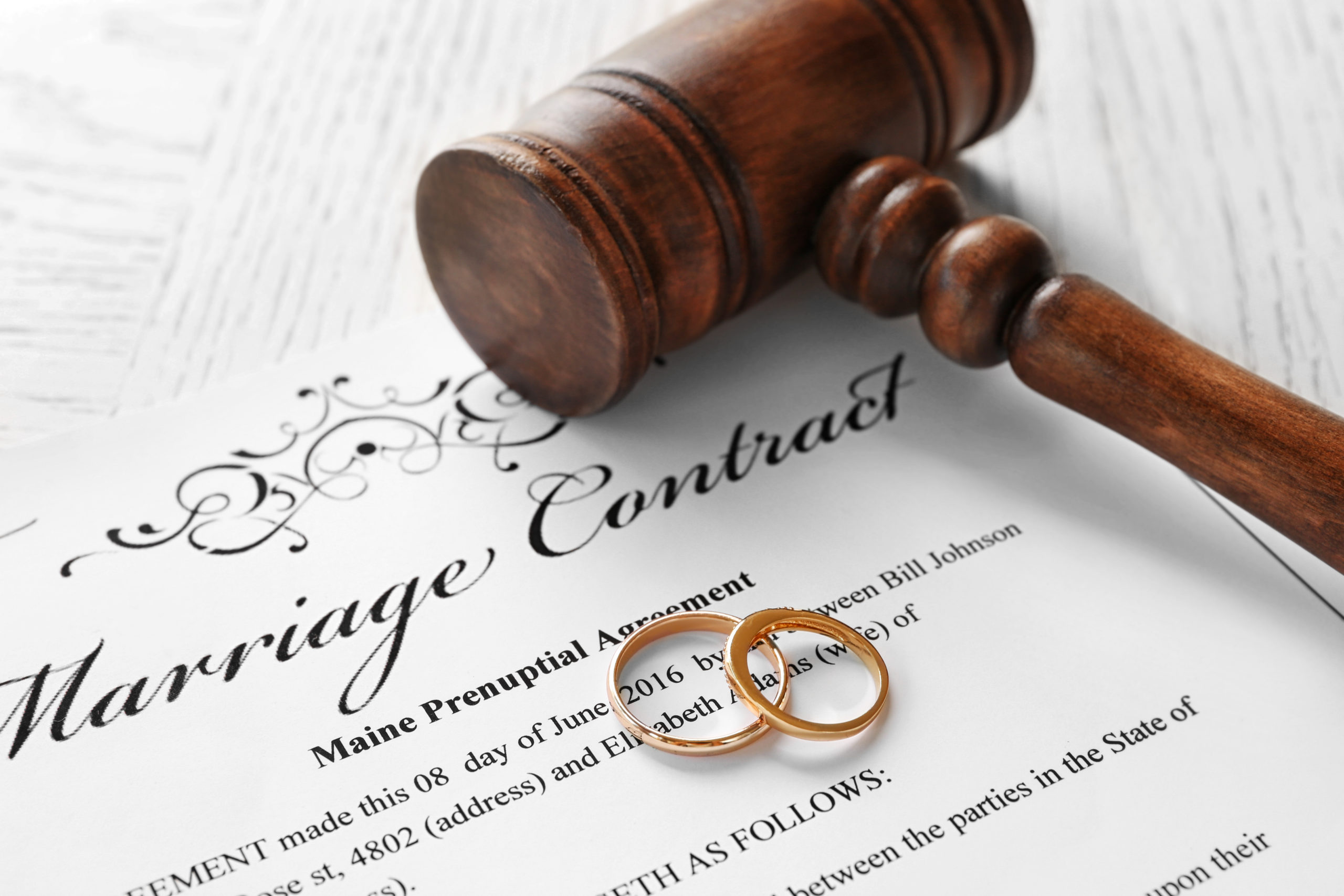 How to Deal with a Hostile Spouse During Divorce - Golden wedding rings with judge gavel on marriage contract, closeup